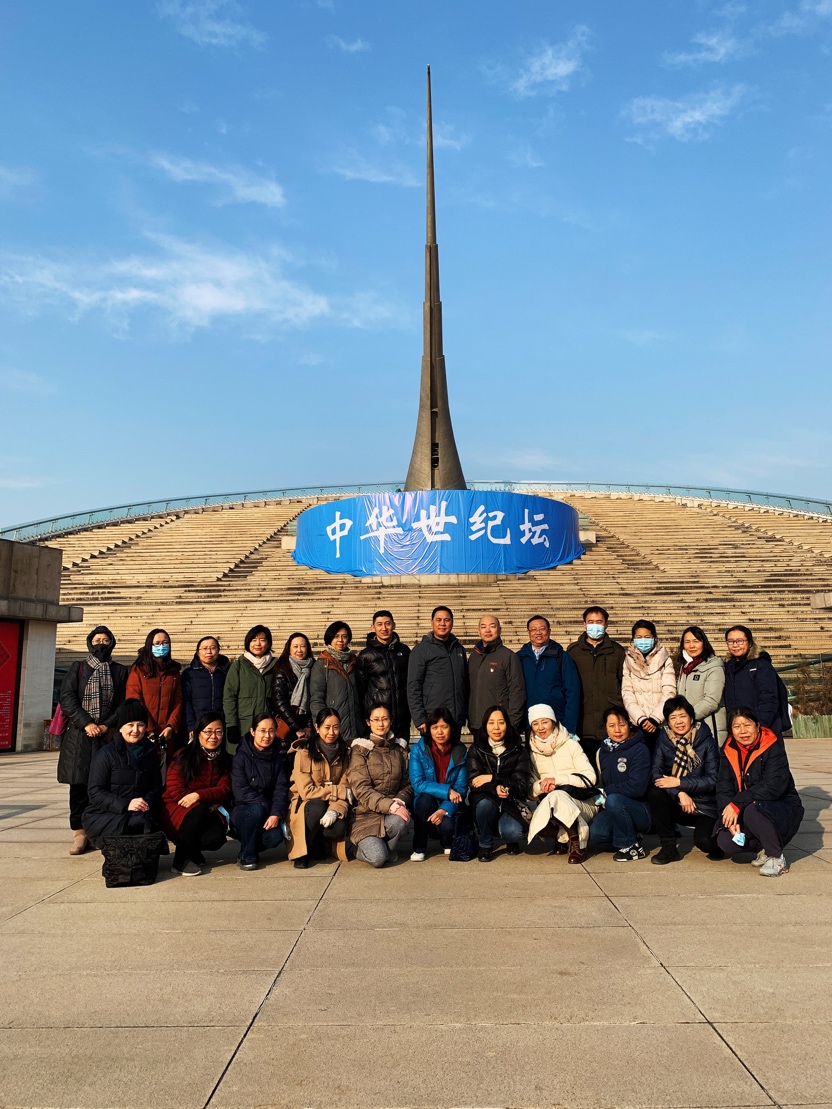 说明: A group of people posing for a photo in front of a monumentDescription automatically generated